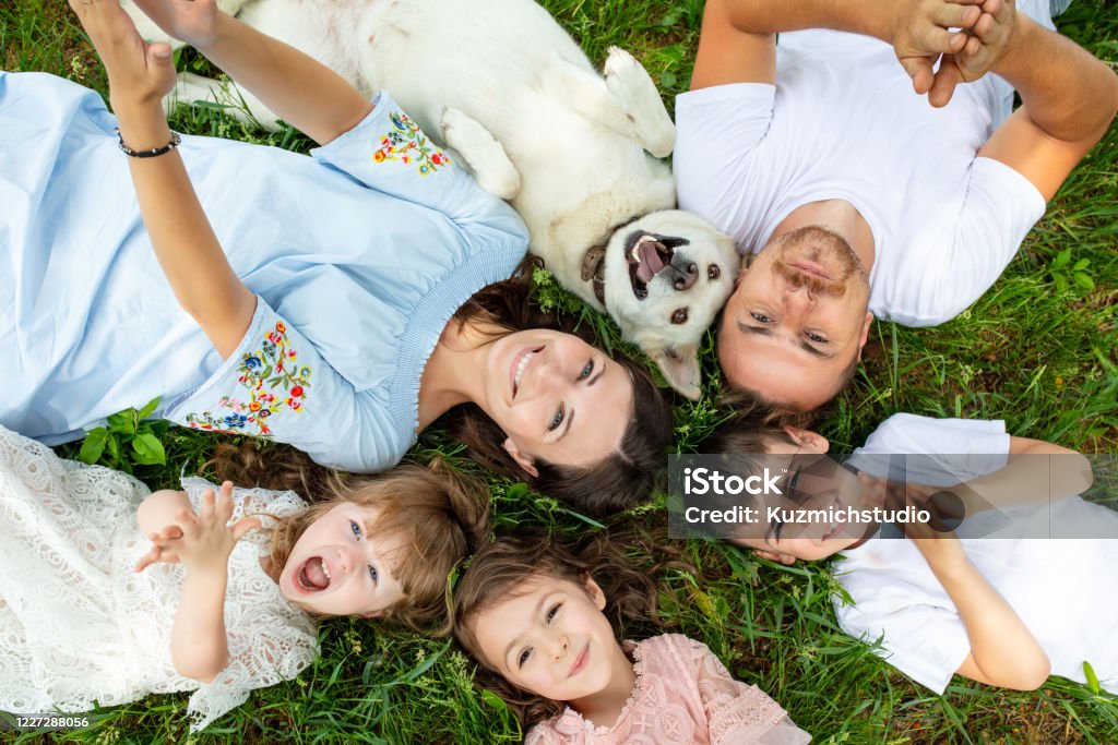 Happy beautiful big family together mother, father, children and dog lying on the grass top view Family Stock Photo