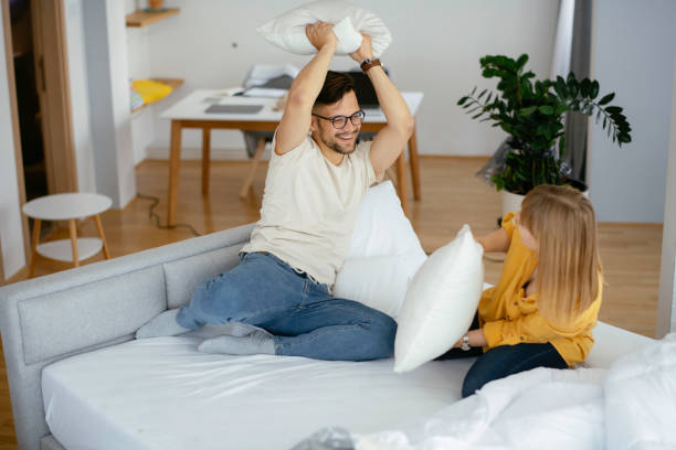 Young couple fighting pillows on the bed. Young couple fighting pillows on the bed. Happy couple having fun at home. sofa bed stock pictures, royalty-free photos & images