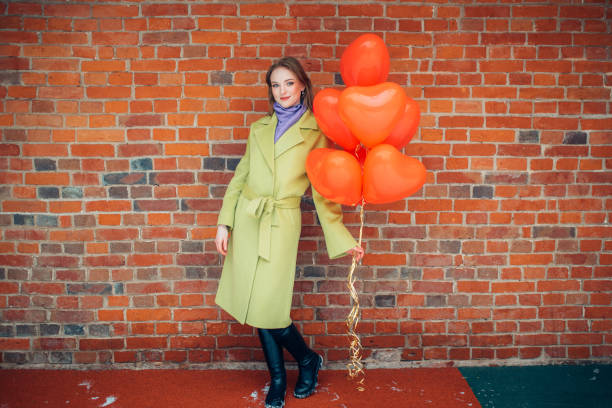 portrait of young and beautiful lady in coat with red air balloons - balloon child winter snow imagens e fotografias de stock