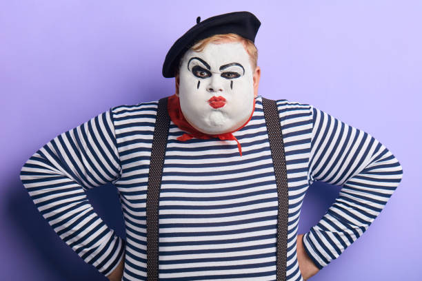 funny plump angry unhappy man playfully looking at the camera close up portrait of funny plump angry unhappy man playfully looking at the camera holding his hands on his hips isolated on blue background. comedy concept mime artist stock pictures, royalty-free photos & images
