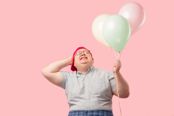 istock Happy man dressed in childish style laughing joyfully while holding air balloons 1227294645