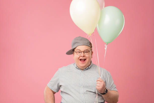 istock Happy man dressed in childish style looking at camera while holding balloons 1227294649