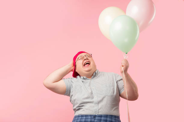 istock Happy man dressed in childish style looking at camera while holding balloons 1227294793