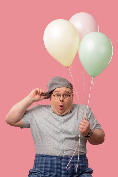 istock Surprised plump man with bugged eyes and rounded mouth, holding air balloons 1227294833