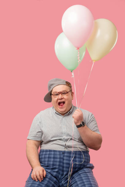 istock Happy man dressed in childish style looking at camera while holding balloons 1227295097