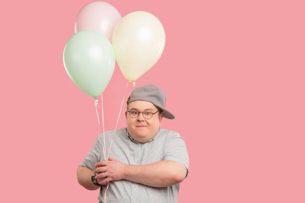 istock Happy man dressed in childish style looking at camera while holding balloons 1227295116