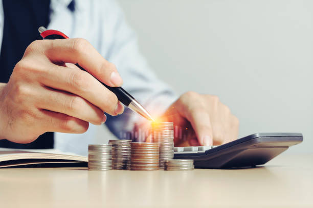 istock Businessman working using calculator with Money (coins) and some stationery on wood table stack in office at home 1227295187