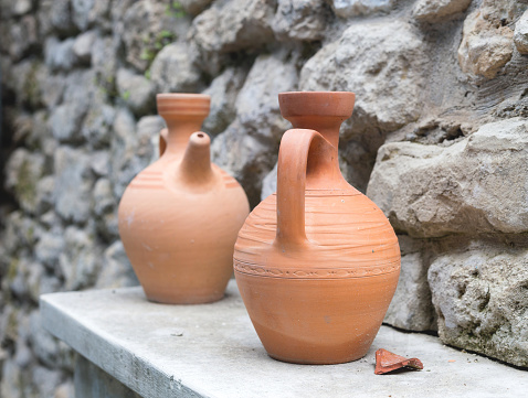 ancient clay jugs on a stone wall background.