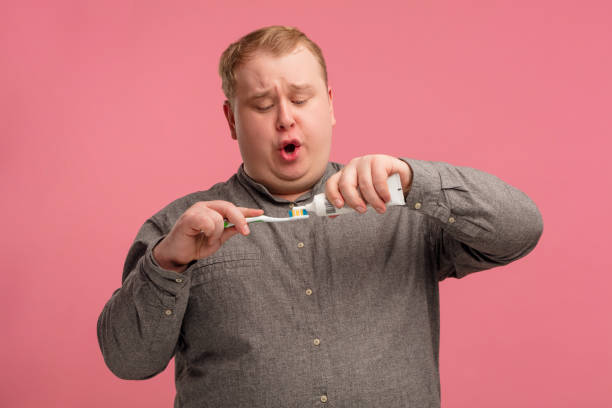 istock Pleasant cheerful man brushing his teeth with vivid emotions on pink background 1227295400