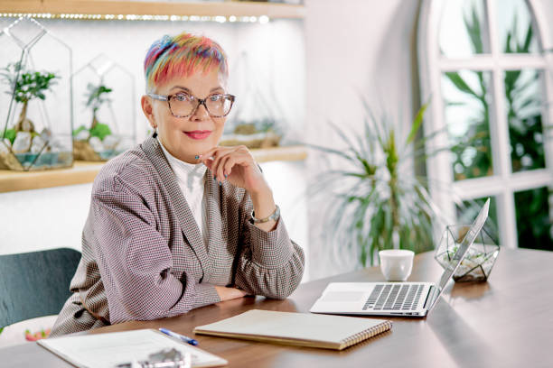 istock Happy business lady sitting on her work place with laptop 1227296111