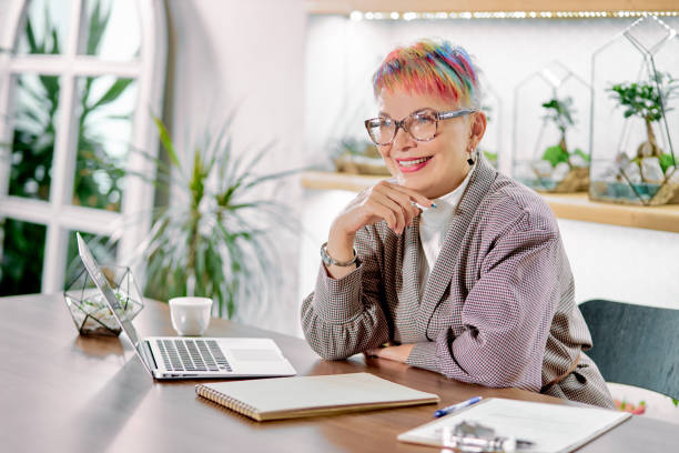 istock Happy business lady sitting on her work place with laptop 1227296496
