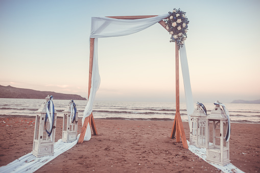 Wedding ceremony on a tropical beach in white. Arch decorated with flowers on the sandy beach. Wedding concept (color toned image)