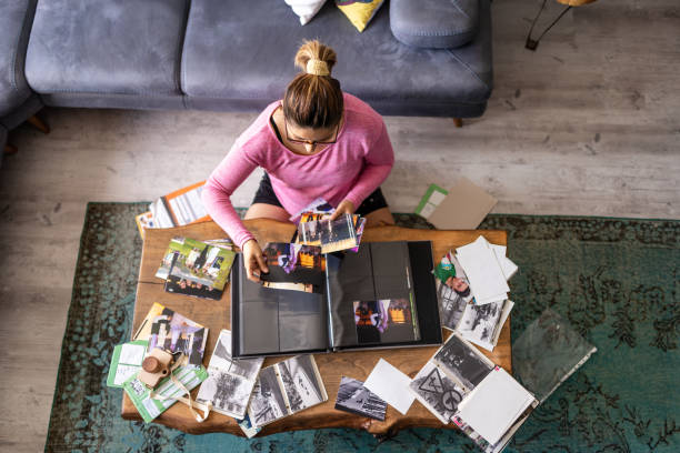 mujer adulta joven añadiendo fotos a un álbum de fotos en casa - inspiración fotos fotografías e imágenes de stock