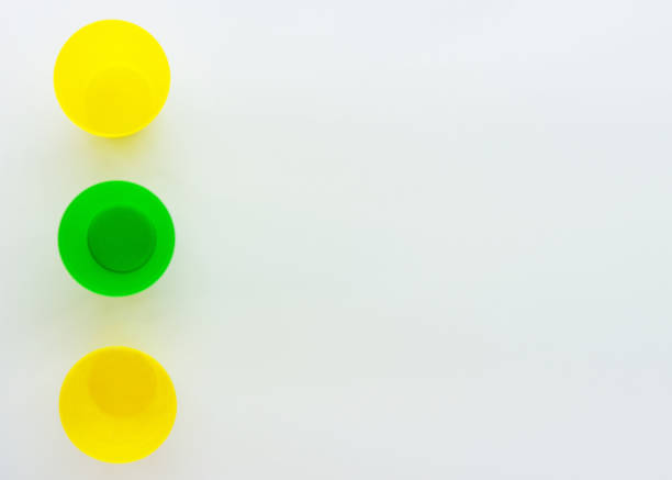 Colorful plastic cups, the view from the top. Yellow and green glass. Composition of plastic dishes. Minimalistic design with space for text. Isolated on a white background.