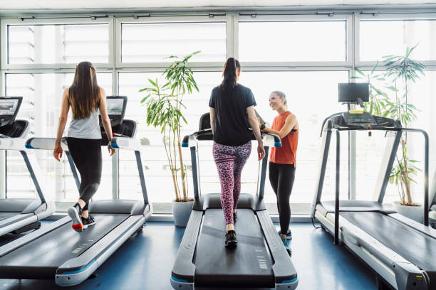 istock Female personal trainer standing next to her client, walking on a treadmill 1227301527