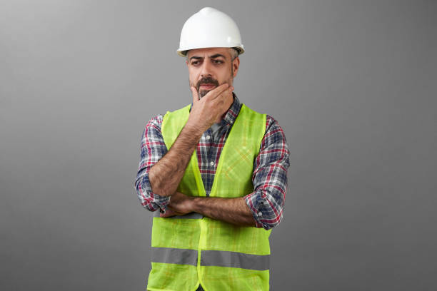 istock Bearded repair man standing with hands crossed on grey background 1227302325