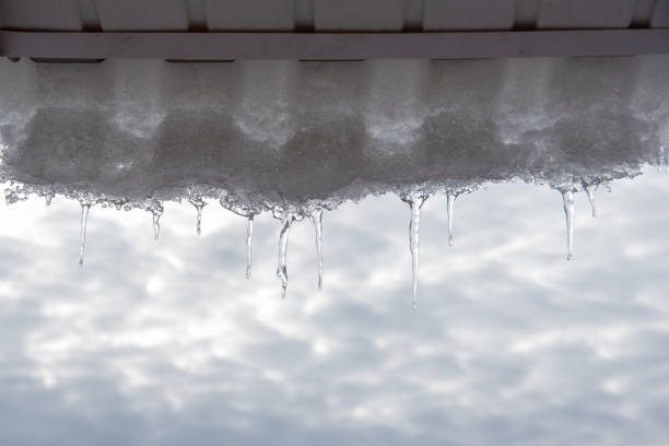 istock Openwork icicle the sun against a blue sky spring landscape with icicles hanging from the roof of the house 1227306004