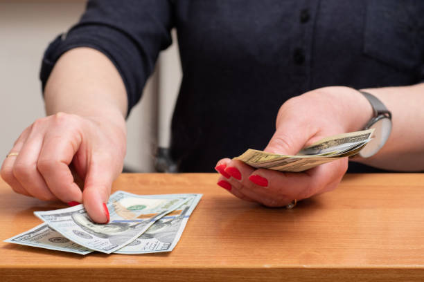 Woman's hands counting hundred dollar bills over the table. selective focus Woman's hands counting hundred dollar bills over the table. selective focus. counting coins stock pictures, royalty-free photos & images