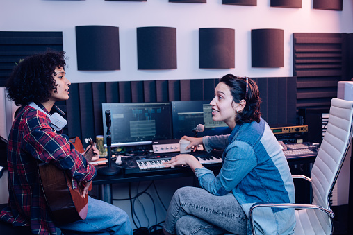 Two young musicians composing music in the studio and having fun.