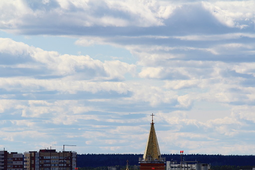 Cross on the golden spire of a Babtist church in the afternoon against a cloudy sky over the horizon in the city of Syktyvkar in Russia.