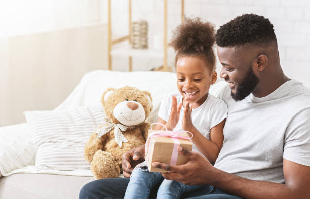 istock Excited black girl taking gift from daddy 1227309080