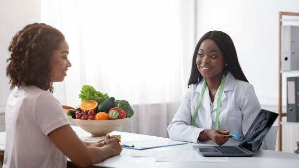 istock Dietician consulting young lady at clinic, using laptop 1227310881