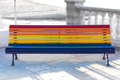 Bench on the beach side street with gay pride flag colors with unfocused background