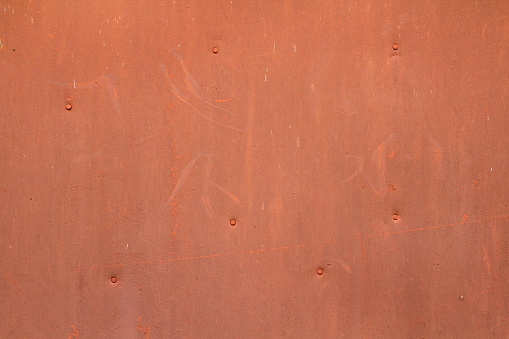 The wall is red orange with scratches and scuffs. Painted iron sheet nailed. The background for text and design. Image for the backdrop and wallpaper.