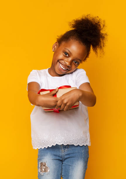 istock Grateful little afro girl getting gift, shy and smiling 1227313491