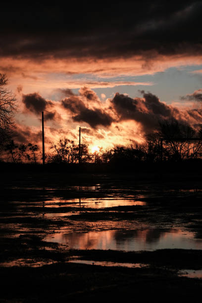 istock Sunset clouds after the rain over field with puddles 1227315812