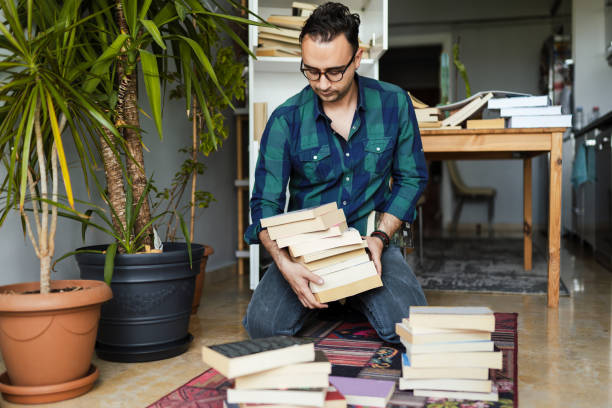 homme millénaire organisant ses collections de livre - disposition photos et images de collection