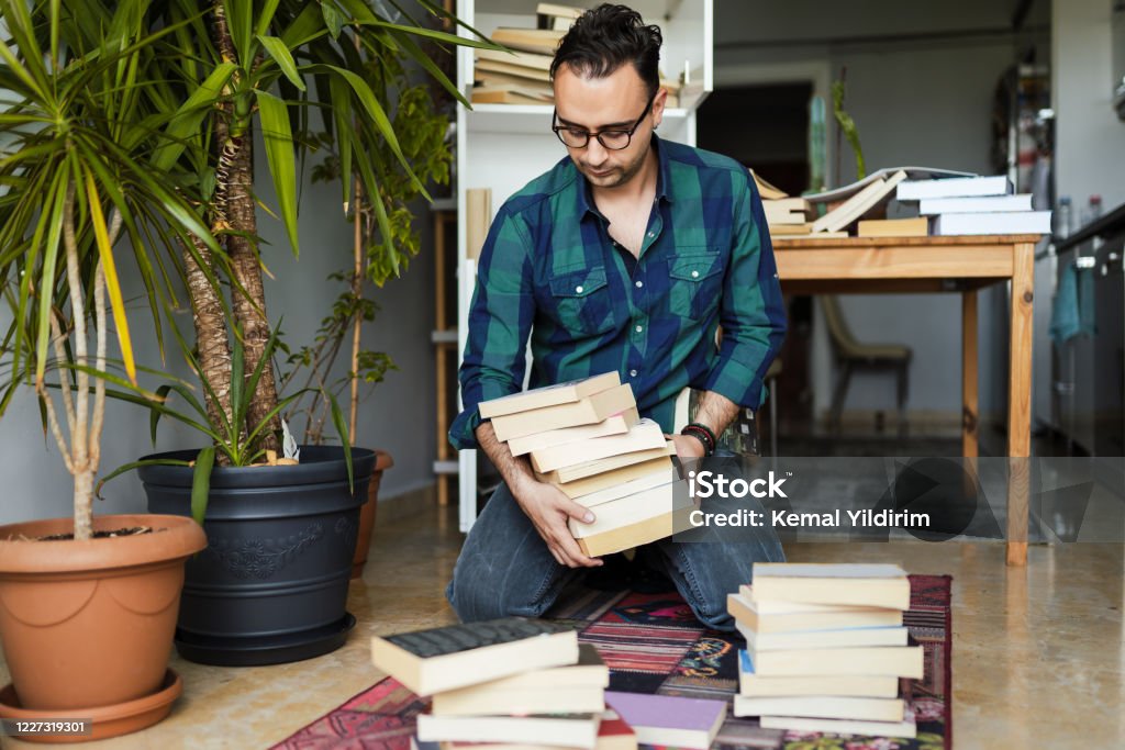 Millennial man organizing his book collections Decluttering Stock Photo