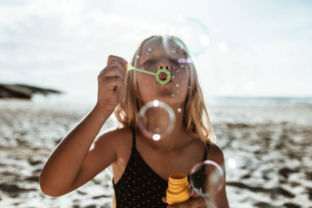 istock Girl blowing soap bubbles on the beach 1227320844