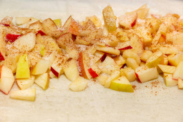 sliced apple slices and sprinkled with sugar and cinnamon to make apple strudel Cooking homemade apple strudel. Sliced and sprinkled with sugar and cinnamon apples on dough apple pie a la mode stock pictures, royalty-free photos & images