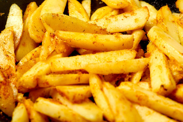Sliced potato with spices. Cooking fried potatoes in a pan.
