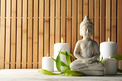 Buddha and candles on white wooden table. Zen concept