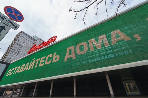 Moscow, Russia - May 2, 2020: Cityscpe in coronavirus pandemic. Wide roads, almost no people and traffic. Placard at the building of cinema Oktyabr' in the New Arbat. Translation - stay home