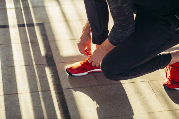 istock Runner getting ready jogging tying running shoes laces while sitting on track 1227330269
