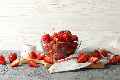 Composition with bowl of tasty strawberry on gray table. Summer berry