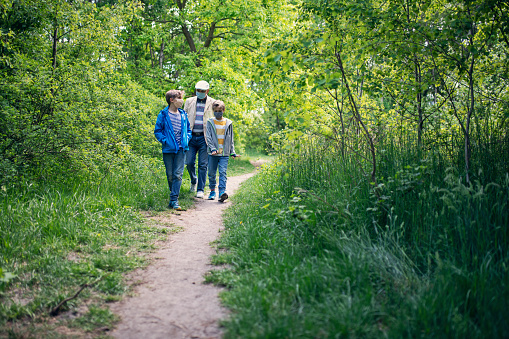 Grandfather and grandsons hiking during the COVID-19 pandemic. Grandfather is telling stories to his grandsons.\n\nNikon D850