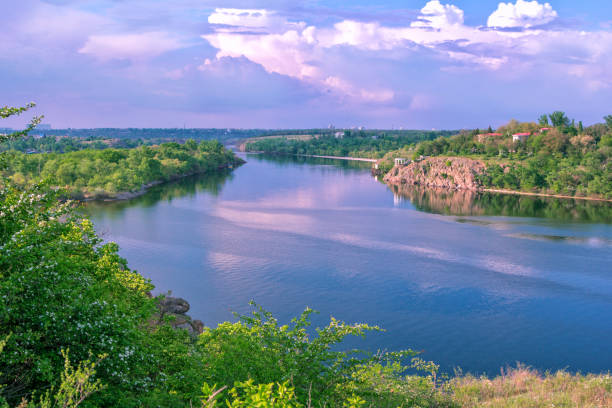 istock Beautiful spring landscape with river, lush forest, cliffs and white clouds 1227332210