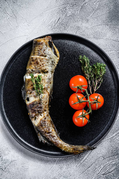 istock Delicious grilled hake with fresh thyme and tomatoes. Black background. Top view 1227333668