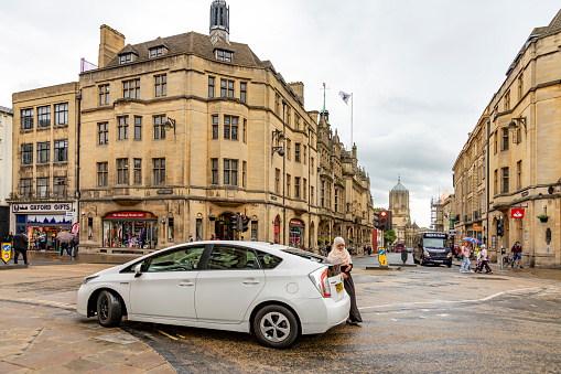 Young Islamic woman getting a lift after a shopping spree in Oxford, Oxfordshire, England, UK.