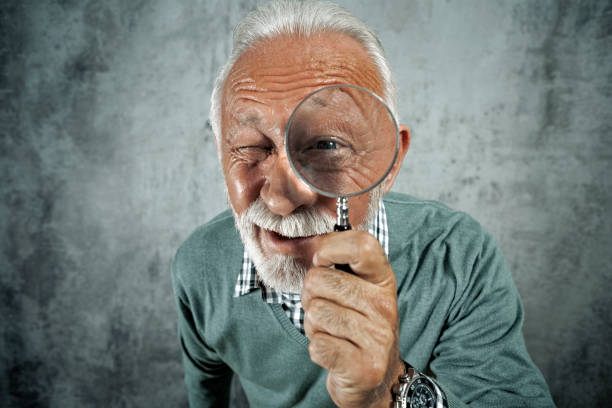istock Senior man with newspaper drinking coffee looking through window daydreaming 1227338012