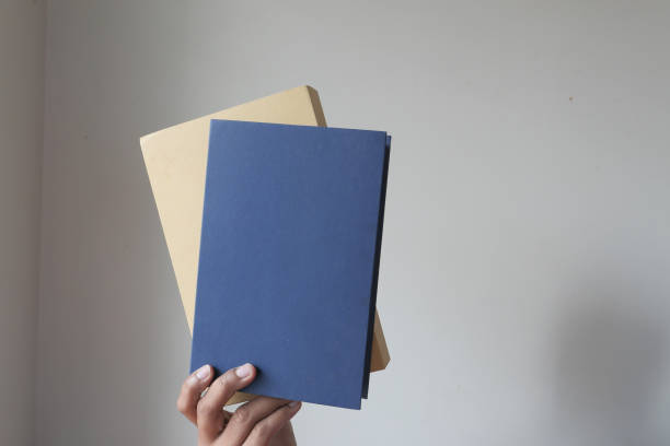 istock hand holding books against a wall 1227345872
