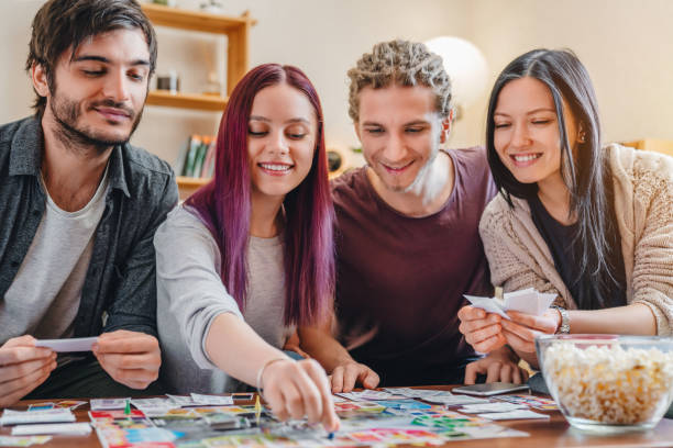 ホームインテリアでテーブルの上でボードゲームをしている友人の若いグループ - leisure games dice indoors table ストックフォトと画像