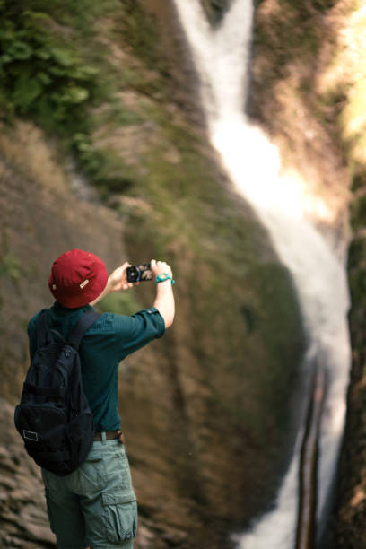 istock Hiker holds smartphone trying to find connection in deep forest with waterfalls. 1227347135