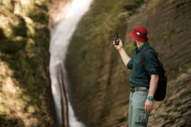istock Hiker holds smartphone trying to find connection in deep forest with waterfalls. 1227347140