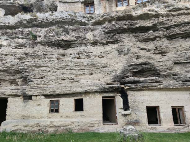istock Old rock monastery. Empty window openings. Second floor with glasses. Green grass 1227347407