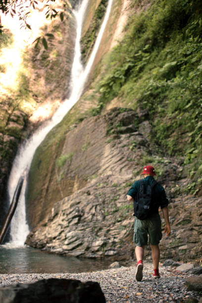 istock Young tourist camping with backpack near a waterfall in forest. 1227348198
